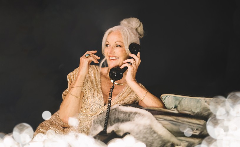 Woman in party outfit holding phone to ear and showing off rings